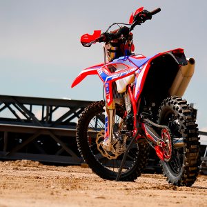 Dirt bike resting on it's own two wheels in a garage because it has a kickstand installed