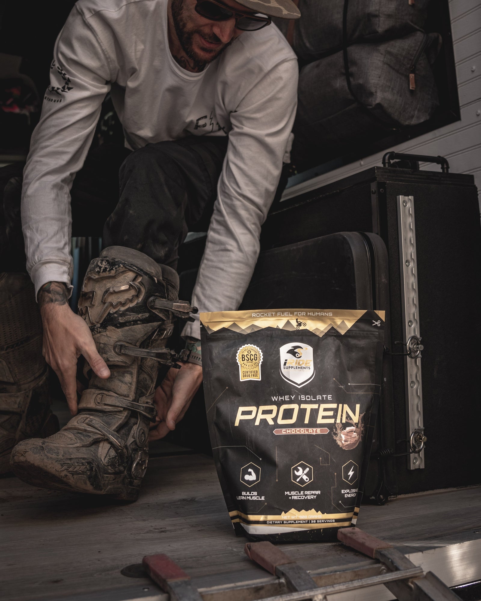 Motocross rider getting ungeared from riding a dirt bike ride. They have a bag of iRide Supplements Protein for a recovery drink post exercise.